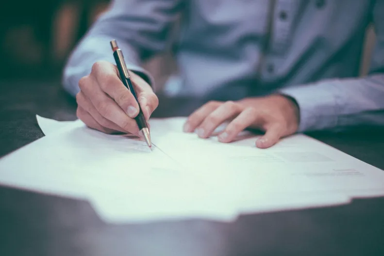 Una mano firma un atto